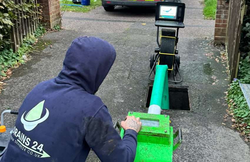 A high-definition image of a drainage engineer in Kingston Upon Thames performing a pipe relining with visible resin liner and inspection camera, showing professional drain repair work.