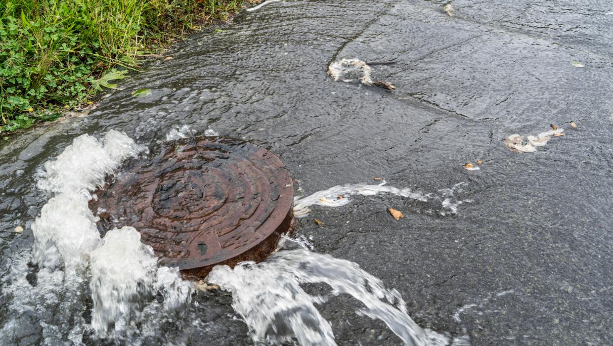 overflowing manhole outside a Kingston home while the homeowner stays at a safe distance